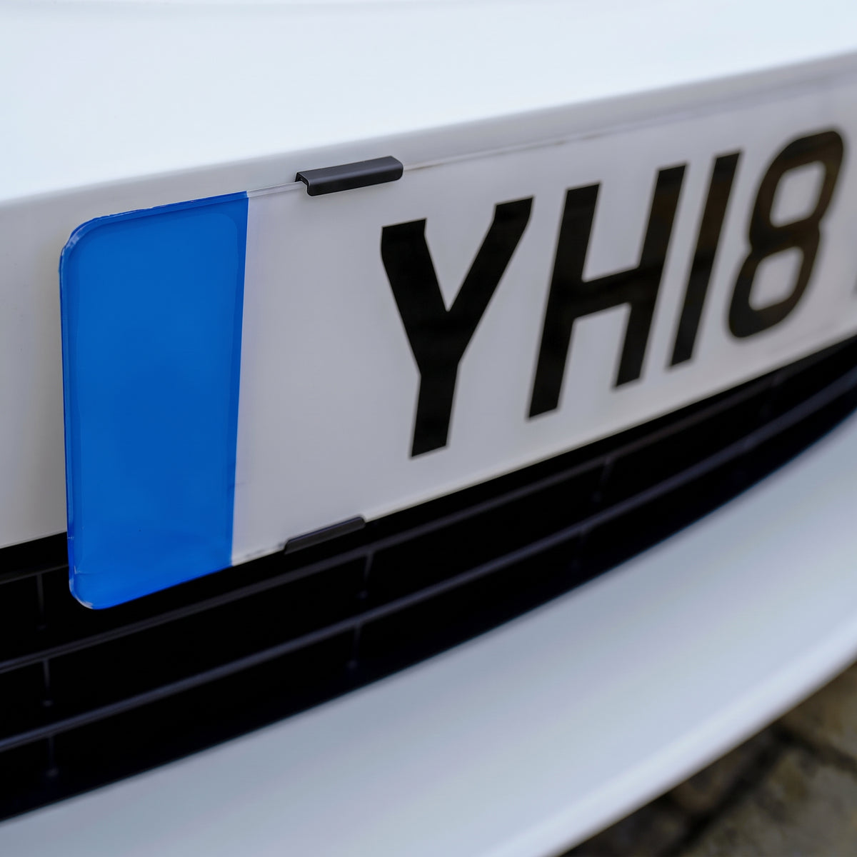 Close-up of a UK number plate edge held by a black PLEXICLICK® clip