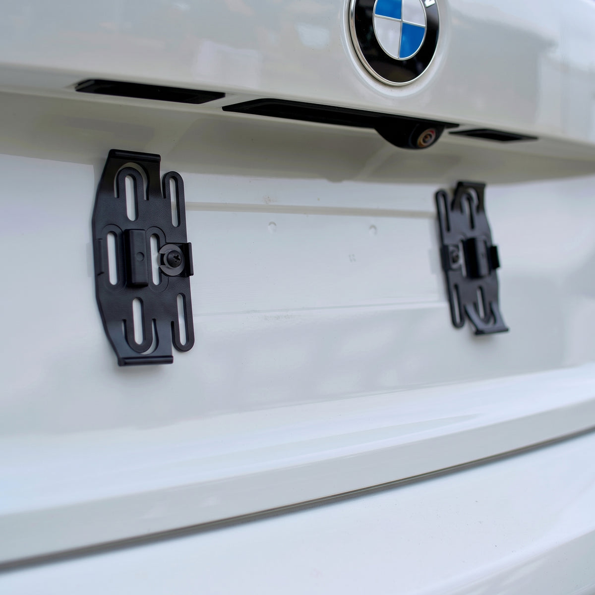 Black PLEXICLICK® V1.3D UK clips screwed to the car's existing number plate mounting points