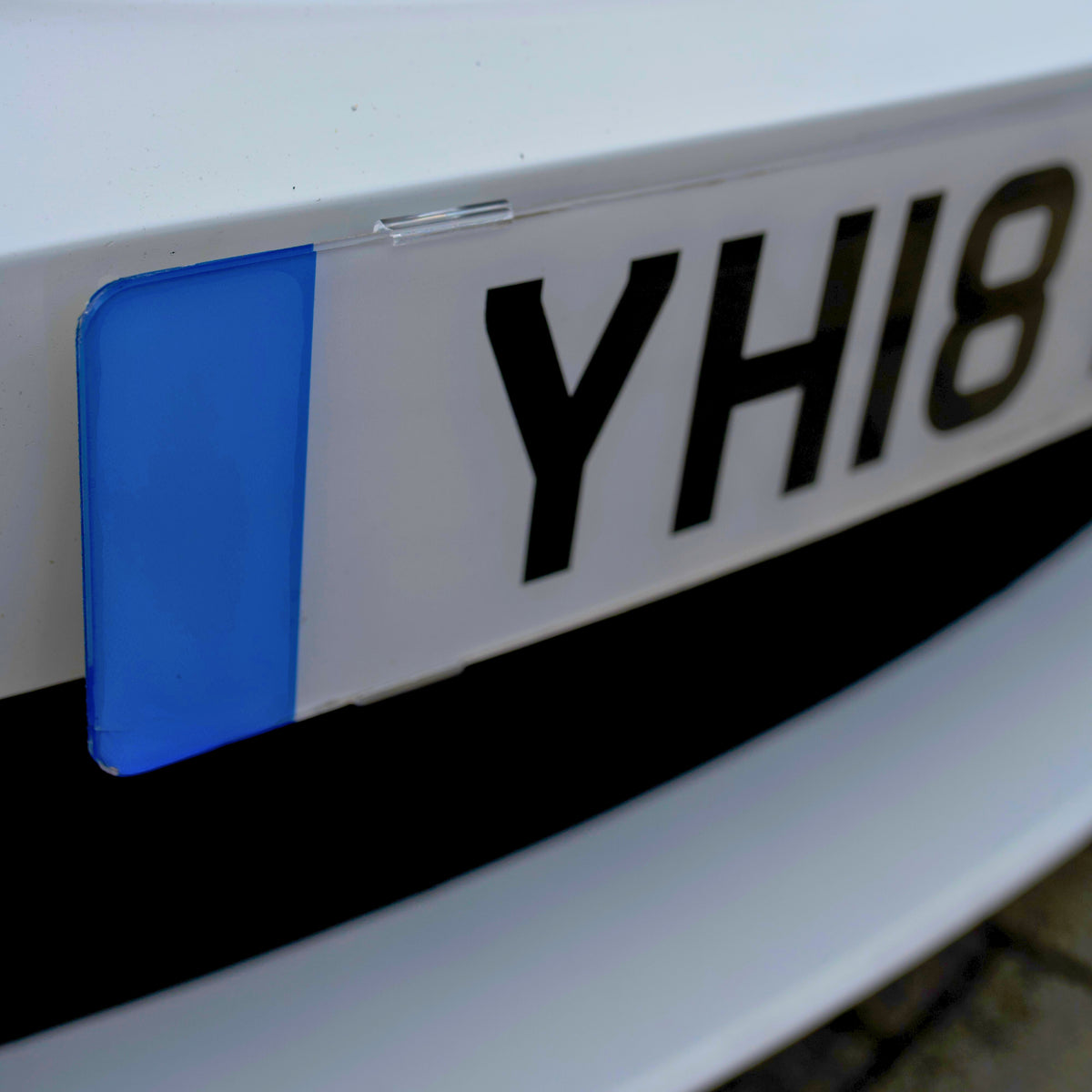Close-up of a UK number plate edge held by a clear PLEXICLICK® clip